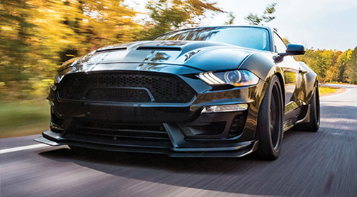 A Preferred Customer's tuned Mustang races along a road in the fall.